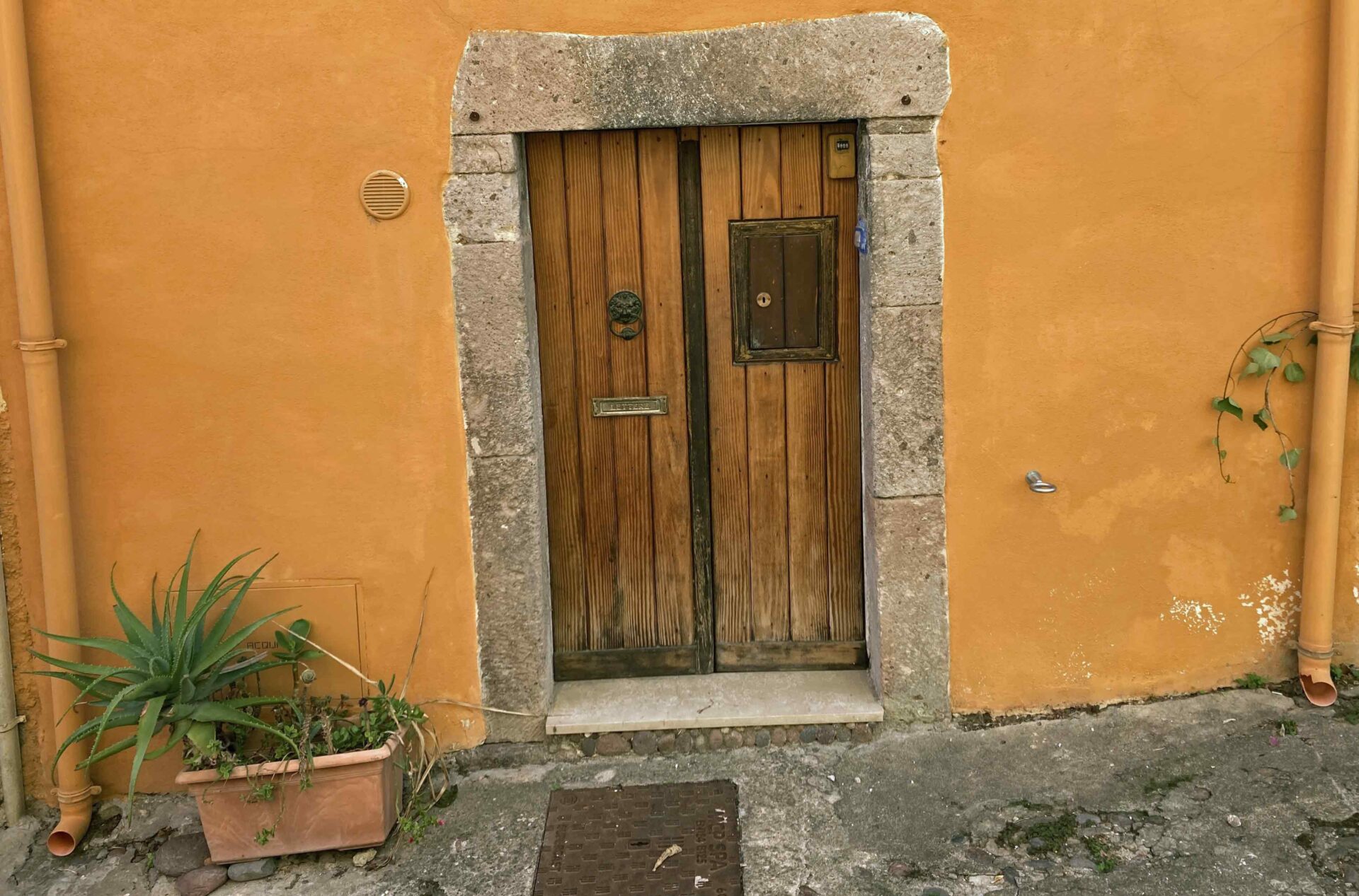 Beispiel für eine Eingangstüre. Hier sieht man eine zweiteilige Holztüre, die mit ca. 30 cm breiten Natursteinen (Sandsteinen) eingefasst ist.